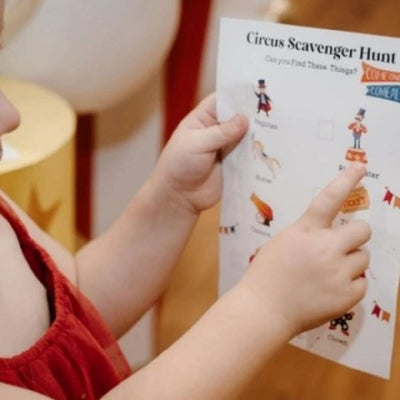 circus theme scavenger hunt game checklist being held by a young girl at a circus themed birthday party