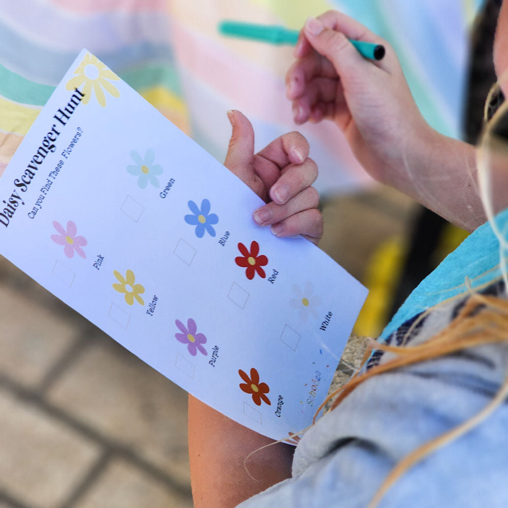 Young girl ticking items off a daisy themed scavenger hunt checklist at a daisy themed kids birthday party