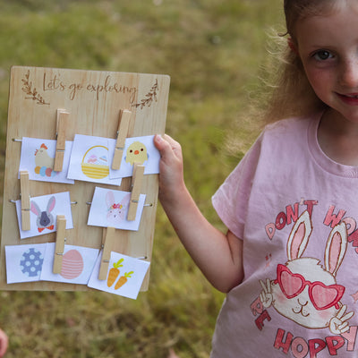 easter scavenger hunt game with all the clue cards found on a lets go exploring board. This is being held up by a young girls in an Easter themed T-Shirt