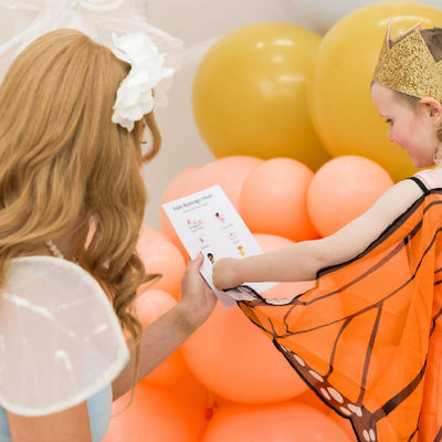 A little girl dressed as a fairy finding the fairy themed items in a scavenger hunt printable party game