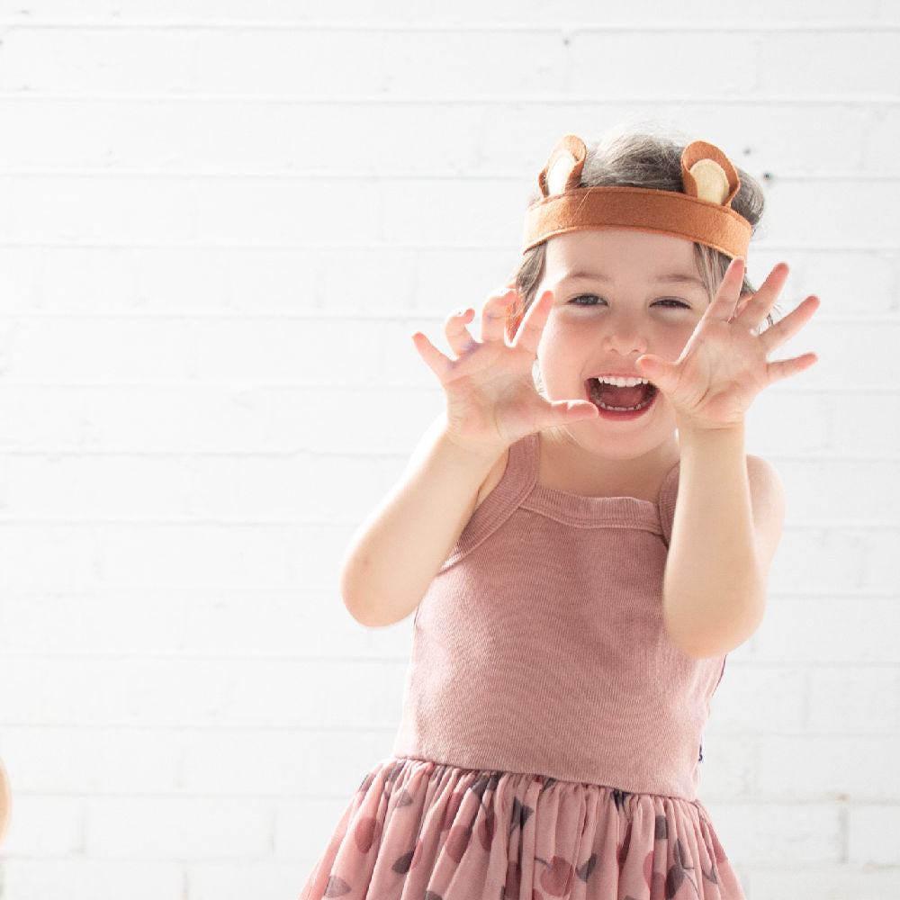 Felt bear ears being worn by a young girl with her hands out like claws of a bear