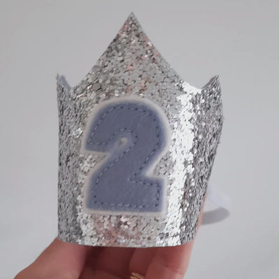 silver birthday crown for a 2nd birthday made from silver glitter fabric with a pale blue felt 2 on the front